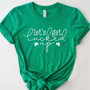 May include: Green t-shirt with white text that says "Let's get lucked up" with shamrock symbols on either side of the word "up".