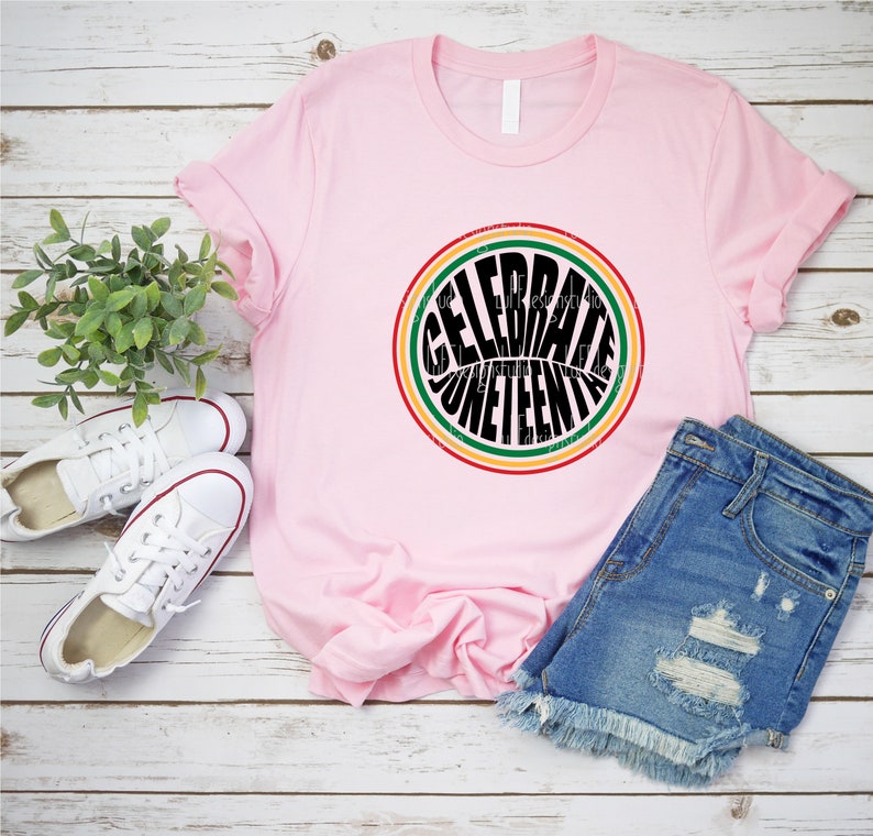 K&ouml;nnte beinhalten: Pinkes T-Shirt mit einem schwarzen Kreis-Motiv, auf dem in einer Retro-Schriftart "Celebrate Juneteenth" steht. Der Kreis ist von roten, gelben und gr&uuml;nen Streifen umgeben.