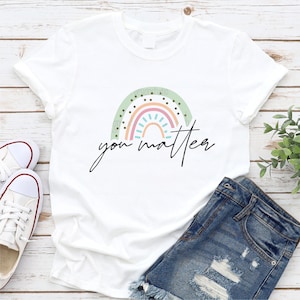 May include: White t-shirt with a rainbow design and the text "you matter" in black.