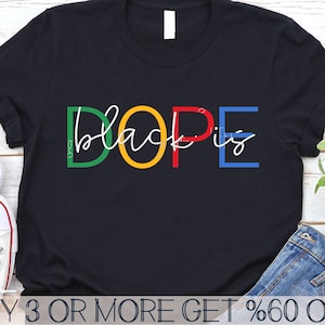 May include: Black t-shirt with the text "black is dope" in colorful letters. The letters are outlined in white and have a rainbow color scheme. The text is centered on the shirt.