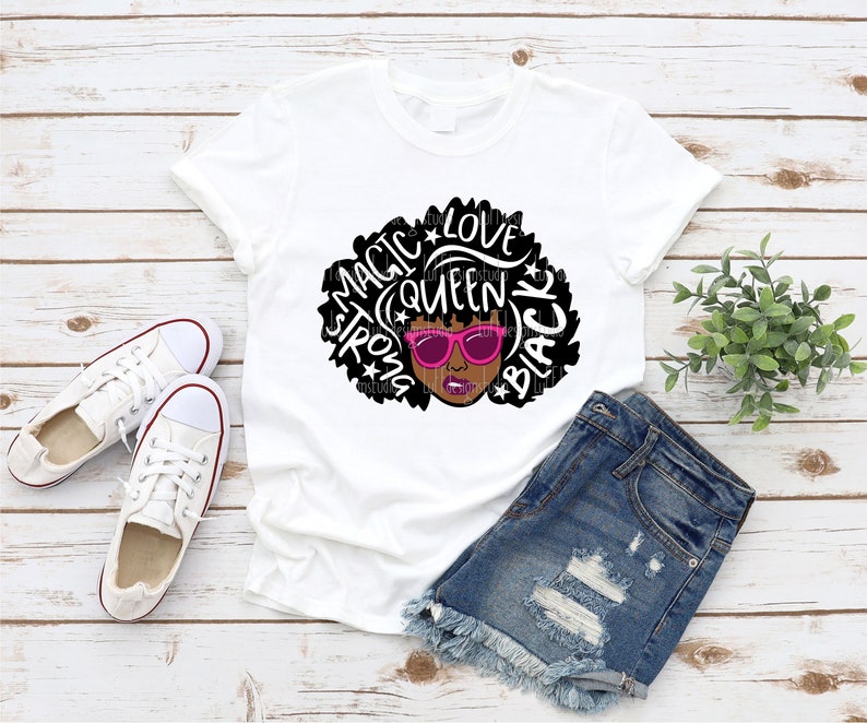 May include: White t-shirt with a black and white graphic of a woman with an afro. The afro is made up of the words "Magic", "Queen", "Strong", "Love", and "Black". The woman is wearing pink sunglasses.