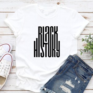 May include: White t-shirt with black text that reads "BLACK HISTORY" in a stylized font.