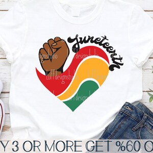 May include: A white t-shirt with a red, yellow, and green heart design. The heart features a raised fist and the word "Juneteenth" in black lettering.