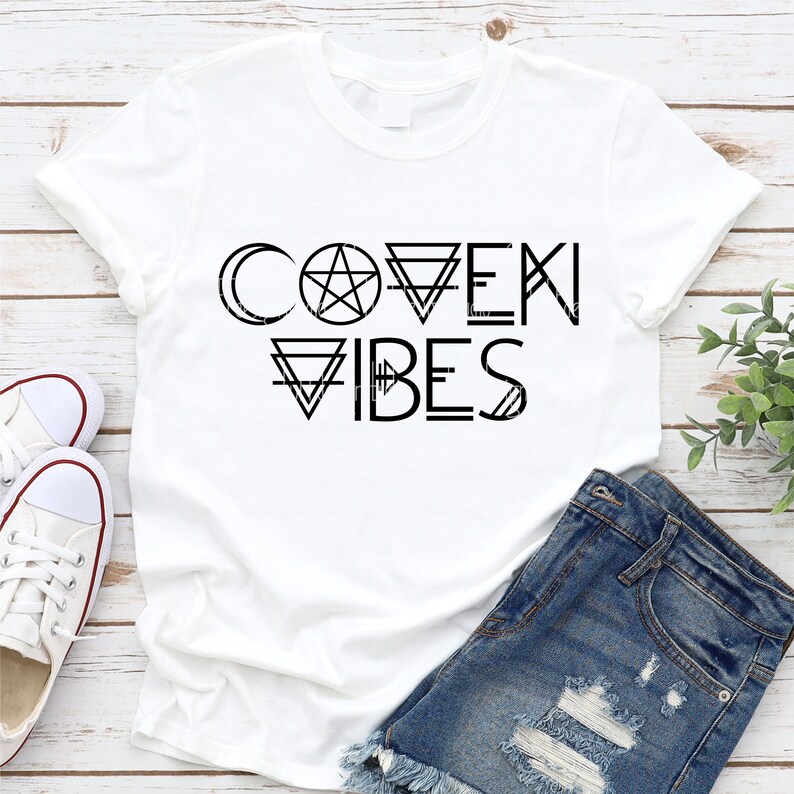 May include: White t-shirt with black text that reads "Coven Vibes" with a pentagram and other geometric shapes.