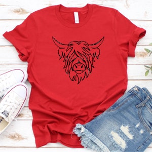 Puede incluir: Camiseta roja con un dibujo de l&iacute;nea negra de la cabeza de una vaca de las tierras altas.