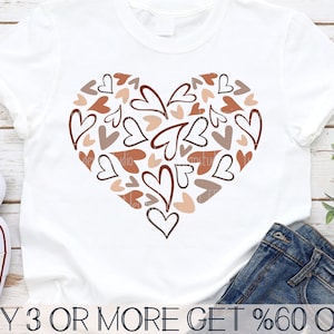 May include: A white t-shirt featuring a brown, pink and orange heart design made up of many smaller hearts. The text "BUY 3 OR MORE GET %60 OFF" is printed at the bottom of the shirt.