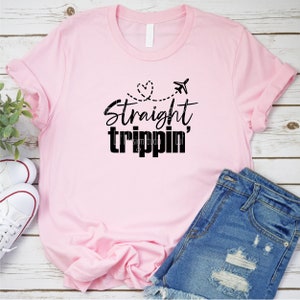 May include: Pink t-shirt with black text that says "Straight trippin'" with a heart and airplane graphic.