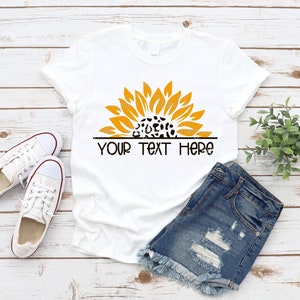 May include: White t-shirt with a yellow sunflower design with a leopard print center. The text "YOUR TEXT HERE" is printed below the sunflower.