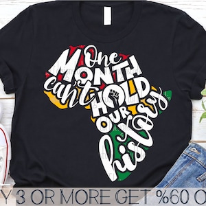 以下が含まれることがあります： アフリカ大陸の白いグラフィックが描かれた黒いTシャツ。グラフィックには「One Month Can't Hold Our History」というテキストが含まれています。