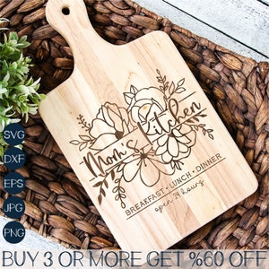 Puede incluir: Una tabla de cortar de madera con un dise&ntilde;o floral y el texto "Mom's Kitchen" con las palabras "Desayuno, Almuerzo, Cena, abierto 24 horas" debajo del dise&ntilde;o floral.