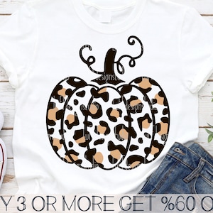 May include: A white t-shirt with a brown and white leopard print pumpkin design. The text "BUY 3 OR MORE GET %60 OFF" is at the bottom of the image.
