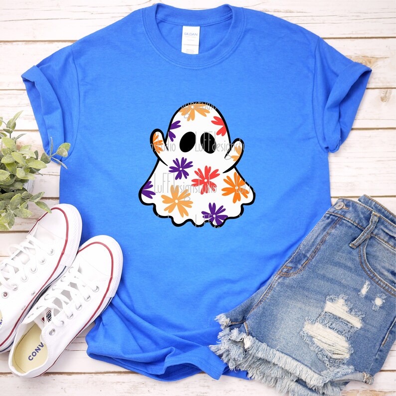 May include: A blue t-shirt with a white ghost design. The ghost is covered in orange, purple, and red flowers.
