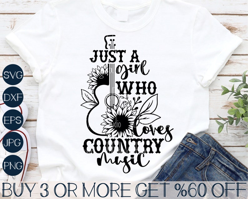 Puede incluir: Camiseta blanca con un dise&ntilde;o gr&aacute;fico negro de una guitarra, girasoles y el texto "JUST A girl WHO Loves COUNTRY Music." La camiseta tambi&eacute;n tiene iconos de tipo de archivo y el texto "BUY 3 OR MORE GET %60 OFF."
