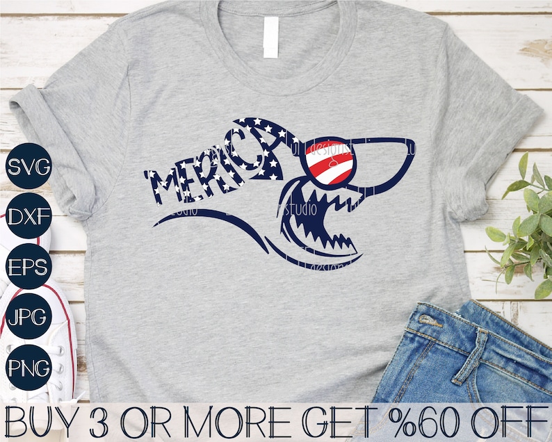 May include: A gray t-shirt with a blue and red shark graphic with the word "MERICA" written in white stars on a blue background. The shark is wearing red, white, and blue sunglasses. The text "BUY 3 OR MORE GET %60 OFF" is at the bottom of the image.