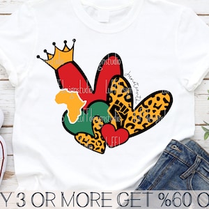 May include: A white t-shirt with a design of a heart made up of smaller hearts in red, green, yellow, and black with a leopard print. The design also includes a crown and the word "Juneteenth".