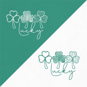 May include: A white graphic design of three shamrocks with the word "lucky" written in cursive below them. The shamrocks are on a green background and the word "lucky" is on a white background.