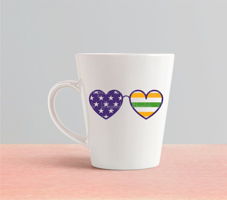 May include: White ceramic mug with a purple and white heart-shaped sunglasses design on one side. The sunglasses have a green, yellow, and purple striped heart on the right lens.