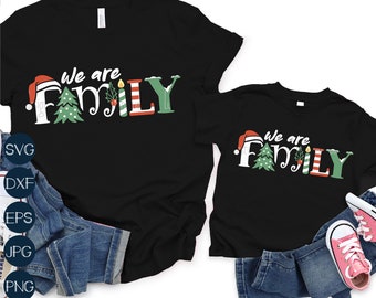 May include: Two black t-shirts with the text "We are Family" in green, red, and white. The text is decorated with Christmas-themed illustrations, including a Santa hat, a Christmas tree, and a candle. The shirts are displayed on a white background with blue jeans and pink sneakers.