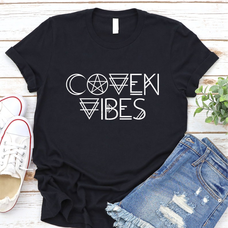 May include: Black t-shirt with white text that reads "Coven Vibes" with a pentagram and other geometric shapes.