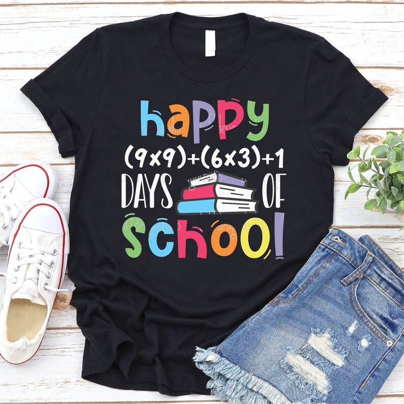 May include: Black t-shirt with the text "happy (9x9)+(6x3)+1 days of school!" in colorful letters. A stack of colorful books is in the middle of the text.