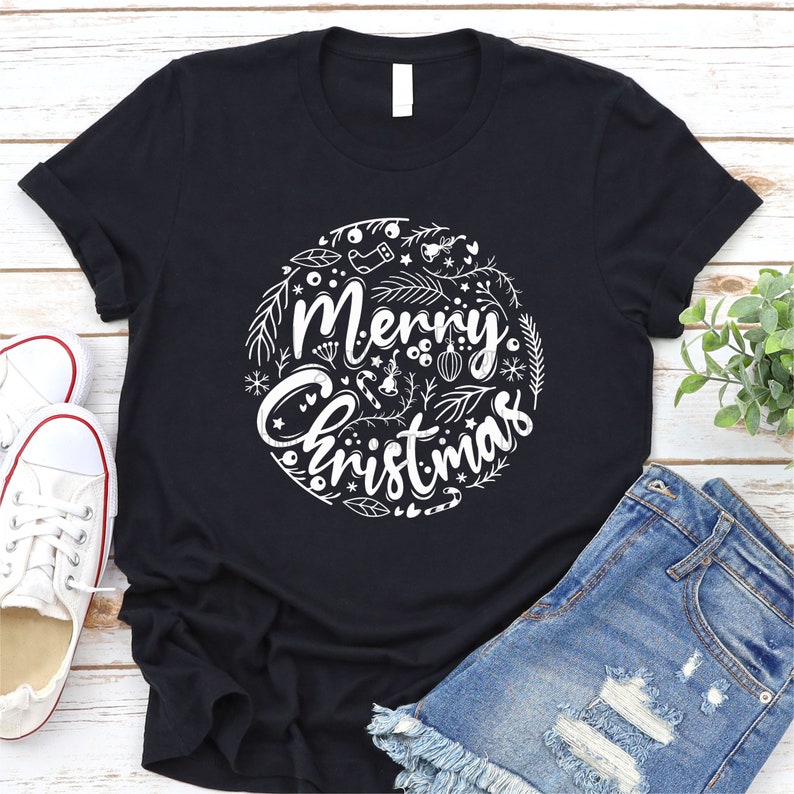 May include: Black t-shirt with a white graphic design of a circle with the text "Merry Christmas" and various Christmas-themed illustrations.