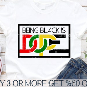 May include: A white t-shirt with a black rectangle containing the text "BEING BLACK IS" and a stylized graphic of the word "DOPE" in red, yellow, green, and black.