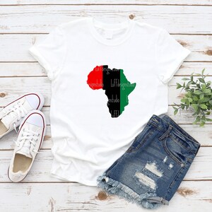 May include: White t-shirt with a black outline of the continent of Africa. The continent is filled with red, black, and green colors, representing the Pan-African flag.