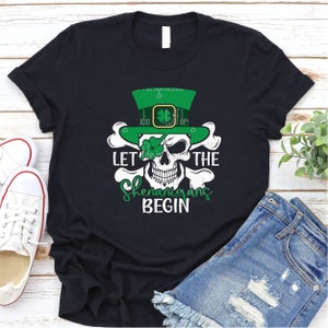 May include: Black t-shirt featuring a white skull wearing a green leprechaun hat and the text "Let the Shenanigans Begin".