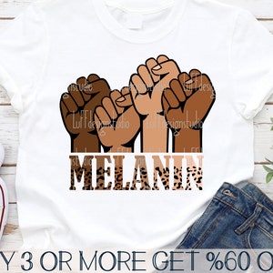 Puede incluir: Tres puños levantados en diferentes tonos de piel, con las palabras "MELANIN" en una fuente de estampado de leopardo debajo. El fondo es una camiseta blanca.