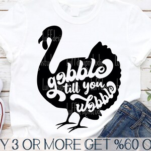 May include: A white t-shirt featuring a black silhouette of a turkey with the text "gobble till you wobble" inside the turkey.