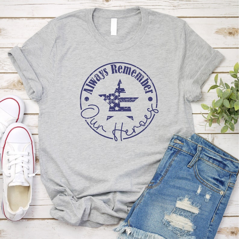 May include: A gray t-shirt with a blue circle design featuring a star with an American flag pattern and the text "Always Remember Our Heroes".