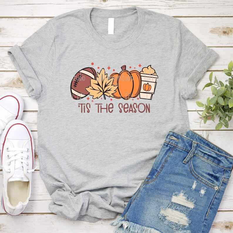 May include: Gray t-shirt with a graphic of a football, fall leaves, pumpkins, and a coffee cup. The text "'Tis the season" is below the graphic.