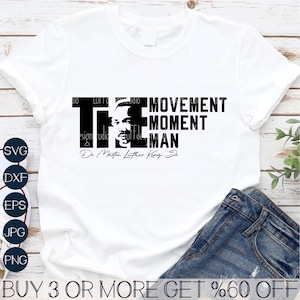 May include: A white t-shirt with a black graphic design featuring a portrait of Martin Luther King Jr. with the text "The Movement, The Moment, The Man" and his signature below.