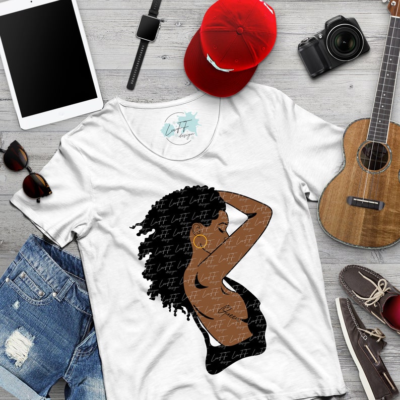 May include: White t-shirt featuring a black and brown graphic of a woman with curly hair and a gold earring. The shirt has the text "Laff Designs" repeated on the graphic. A red baseball cap, sunglasses, and a tablet are also visible.