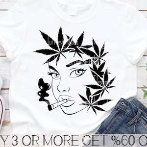 May include: Black and white illustration of a woman's face with marijuana leaves around her head and a cigarette in her mouth. The image is on a white t-shirt.