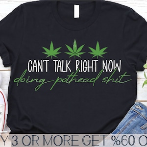 May include: Black t-shirt with a green marijuana leaf design and the text "CAN'T TALK RIGHT NOW doing pothead shit".