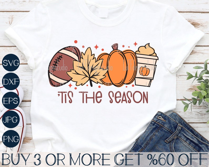 May include: White t-shirt with a graphic design of a football, pumpkin, fall leaves, and a cup of coffee. The text "'Tis the season" is below the graphic.