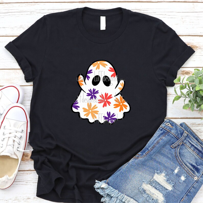 May include: A black t-shirt with a white ghost design. The ghost is covered in colorful flowers with orange, red, purple, and yellow accents.