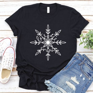 Op de afbeelding: Zwart T-shirt met een wit sneeuwvlokkenontwerp met de tekst "love snow".