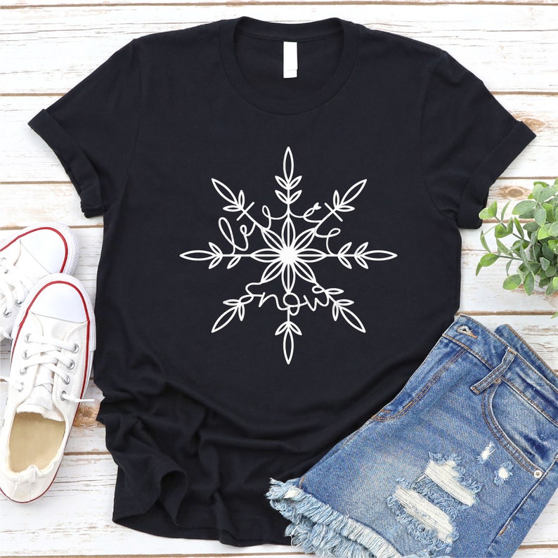 Op de afbeelding: Zwart T-shirt met een wit sneeuwvlokkenontwerp met de tekst "love snow".