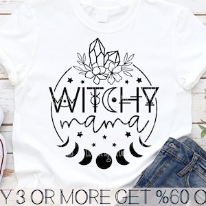 May include: A white t-shirt with a black circle design featuring the text "WITCHY mama" surrounded by stars, moons, and crystals.