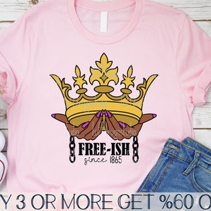 May include: A pink t-shirt featuring a gold crown held by two hands with pink fingernails. The text "FREE-ISH since 1865" is positioned below the crown. The text "BUY 3 OR MORE GET %60 OFF" is at the bottom of the image.