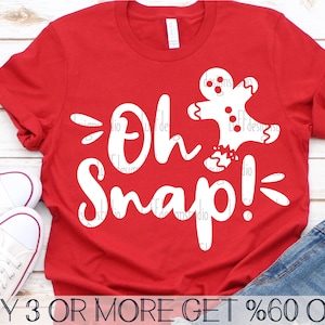 May include: Red t-shirt with a white gingerbread man graphic and the text "Oh Snap!" printed on the front. The text is in a playful, handwritten font.