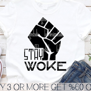 May include: A white t-shirt with a black raised fist graphic and the text "STAY WOKE" in black block letters. The text "BUY 3 OR MORE GET %60 OFF" is printed at the bottom of the image.