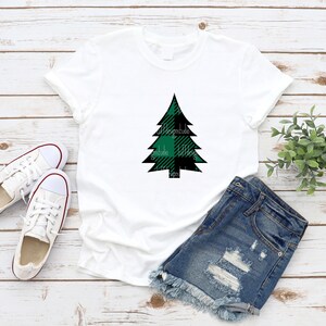 May include: White t-shirt with a green and black plaid Christmas tree design.