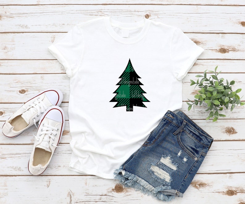 May include: White t-shirt with a green and black plaid Christmas tree design.