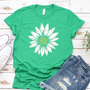 Op de afbeelding: Een groen T-shirt met een witte madeliefje met een geel en oranje luipaardprint in het midden.