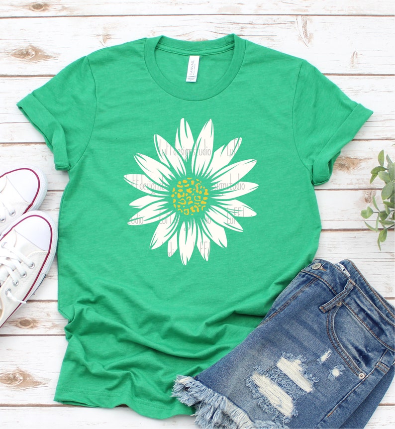 Op de afbeelding: Een groen T-shirt met een witte madeliefje met een geel en oranje luipaardprint in het midden.