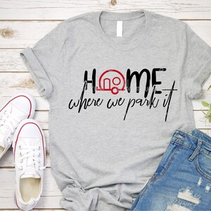 Op de afbeelding: Grijs T-shirt met de tekst "Home is where we park it" en een rood campericoon.