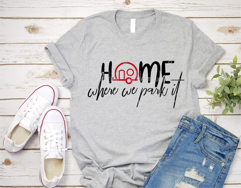 Op de afbeelding: Grijs T-shirt met de tekst "Home is where we park it" en een rood campericoon.